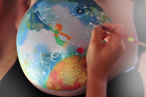 Colorful painted pregnant belly symbolizing planet Earth, with a meadow, sky, and birds. An artistic expression of care for nature and celebration of new life, ideal for a photoshoot or baby shower. - full resolution